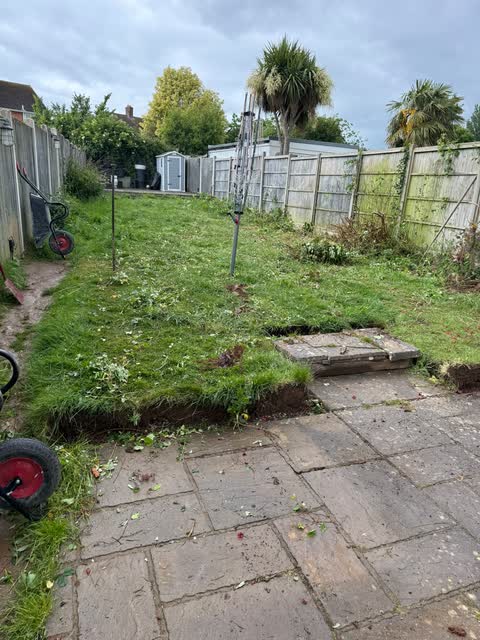 The same long garden before work, with uneven lawn and old paving
